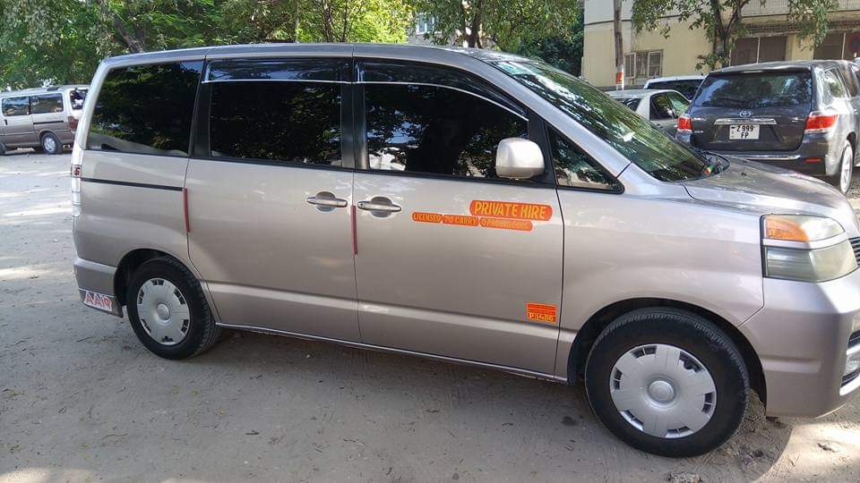 Private hire minivan on a dusty road in Zanzibar — 'Private Hire' sticker, licensed to carry passengers
