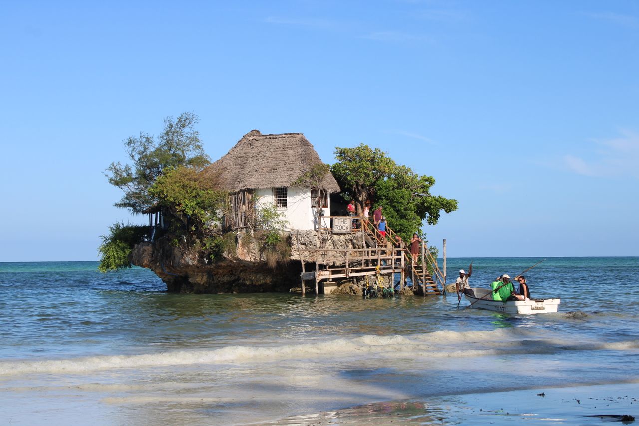 The Rock Restaurant — iconic coral outcrop dining, thatched roof, wooden stairs, boat transfer at Pingwe beach