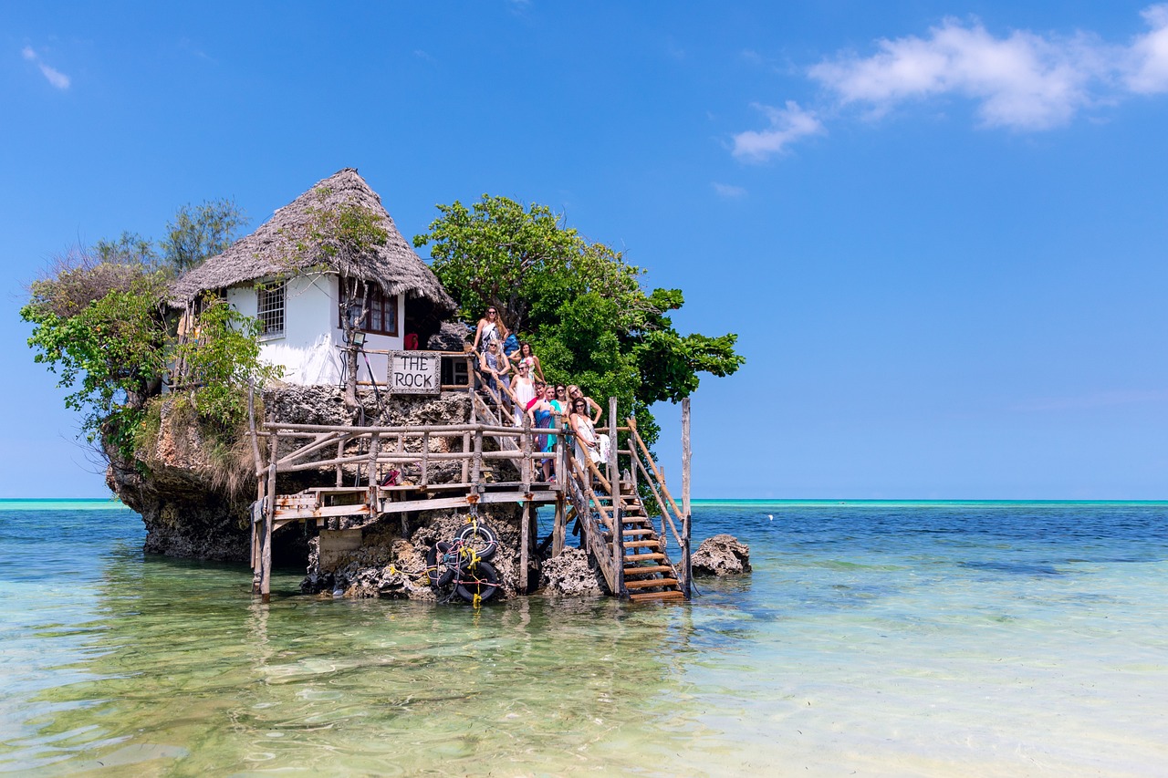 The Rock Restaurant — iconic building on coral outcrop, turquoise ocean, tourists on wooden stairs
