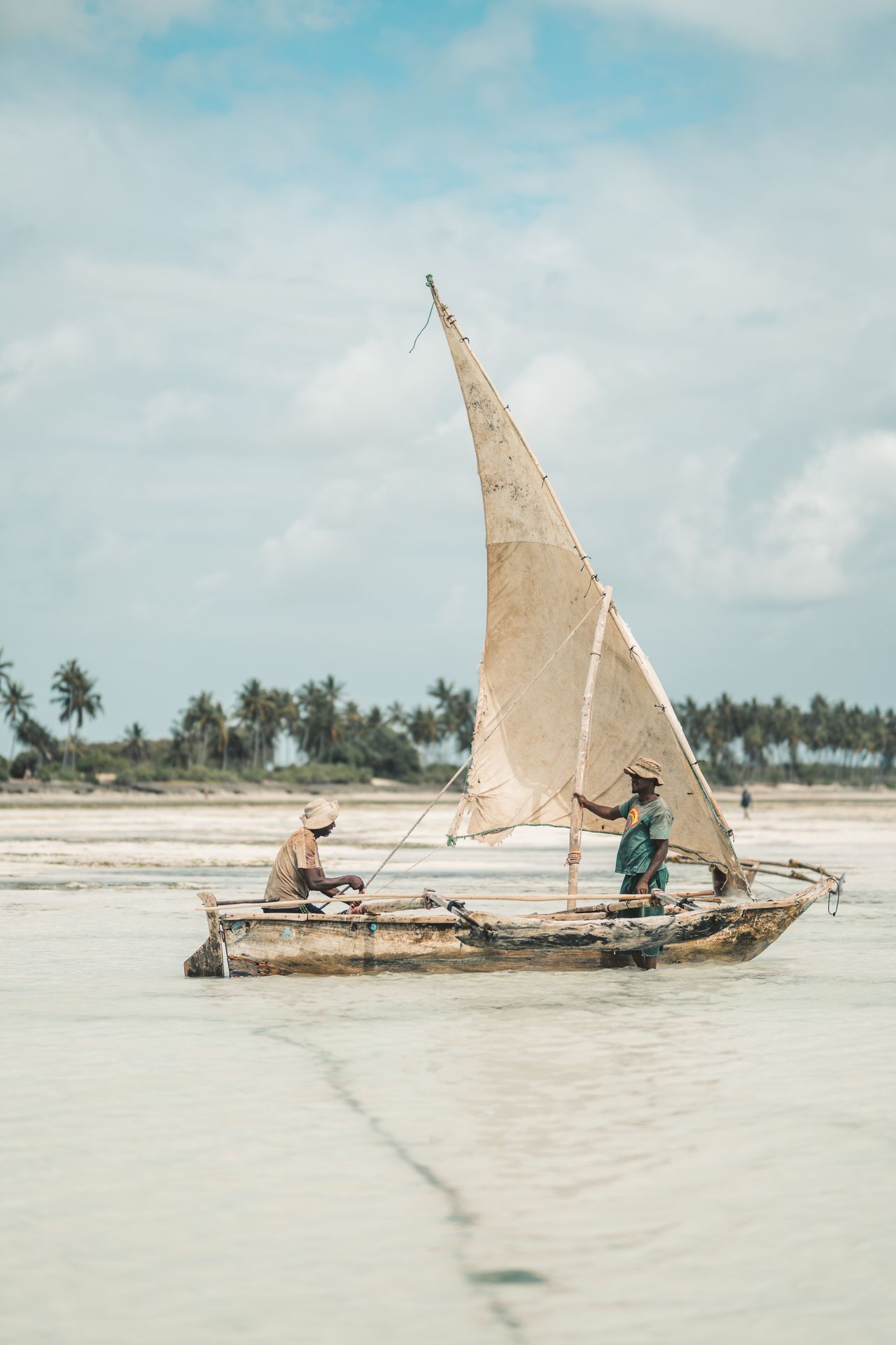 Traditional Ngalawa boat — local fishermen, outrigger canoe, triangular sail, shallow coastal waters