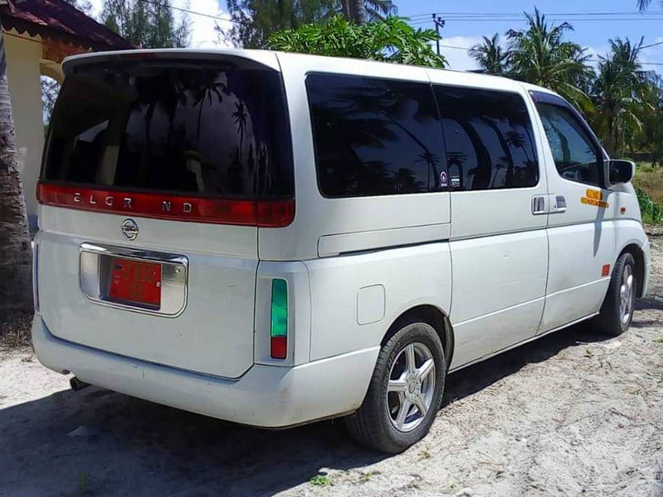 White passenger van on sandy ground — tinted windows, spacious interior, tourism transport